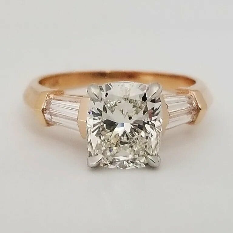 An engagement ring with a cushion cut diamond and baguette diamonds.
