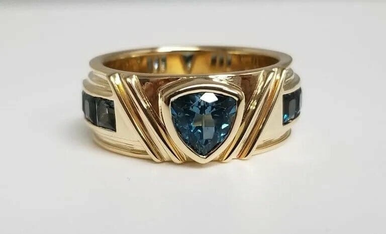 A gold ring with blue topaz and black diamonds.