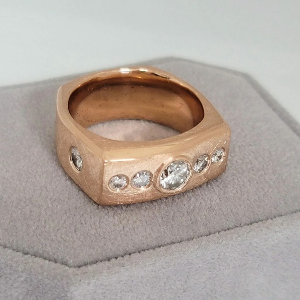 A rose gold ring with diamonds on it.