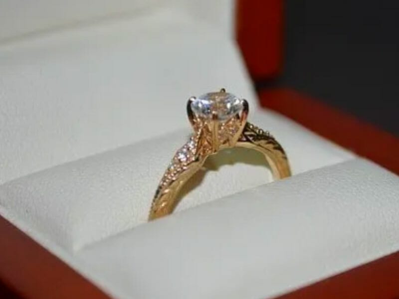 A yellow gold engagement ring in a box.