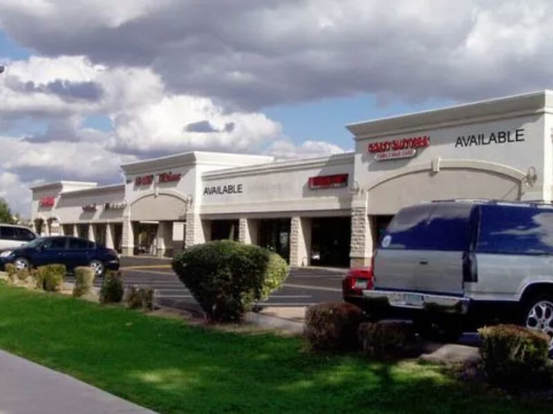 A parking lot with cars parked in front of a shopping center.