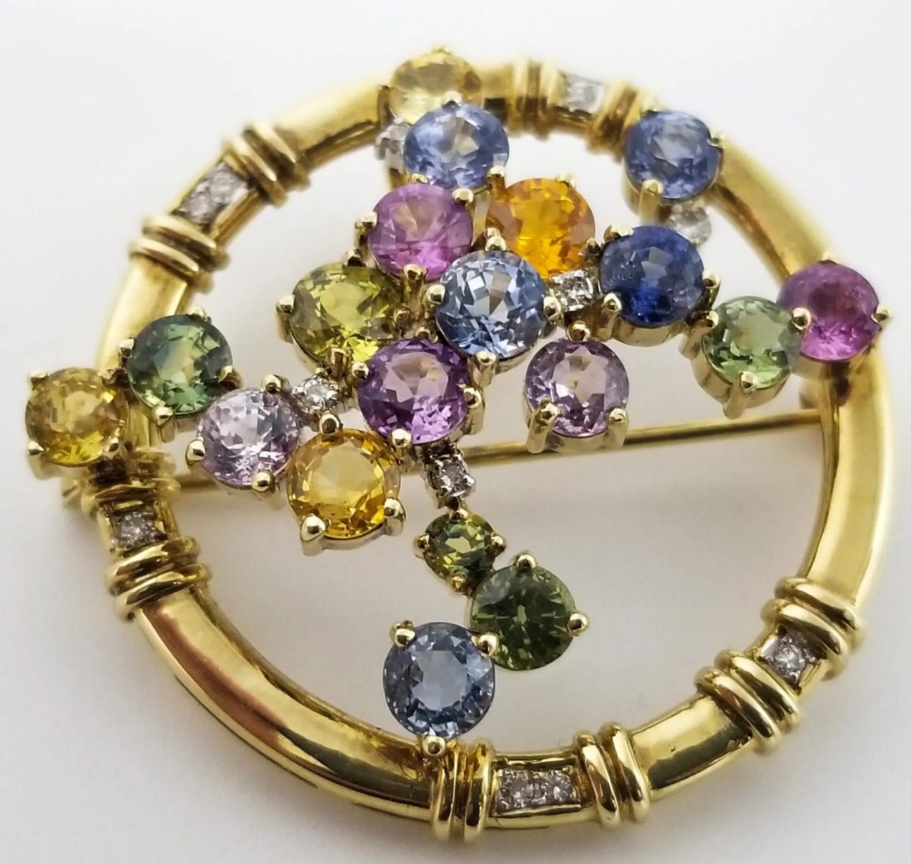 A yellow gold broochle with multi colored sapphires and diamonds.