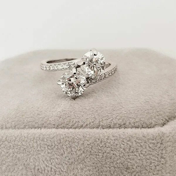 An engagement ring with two diamonds on top of a cushion.