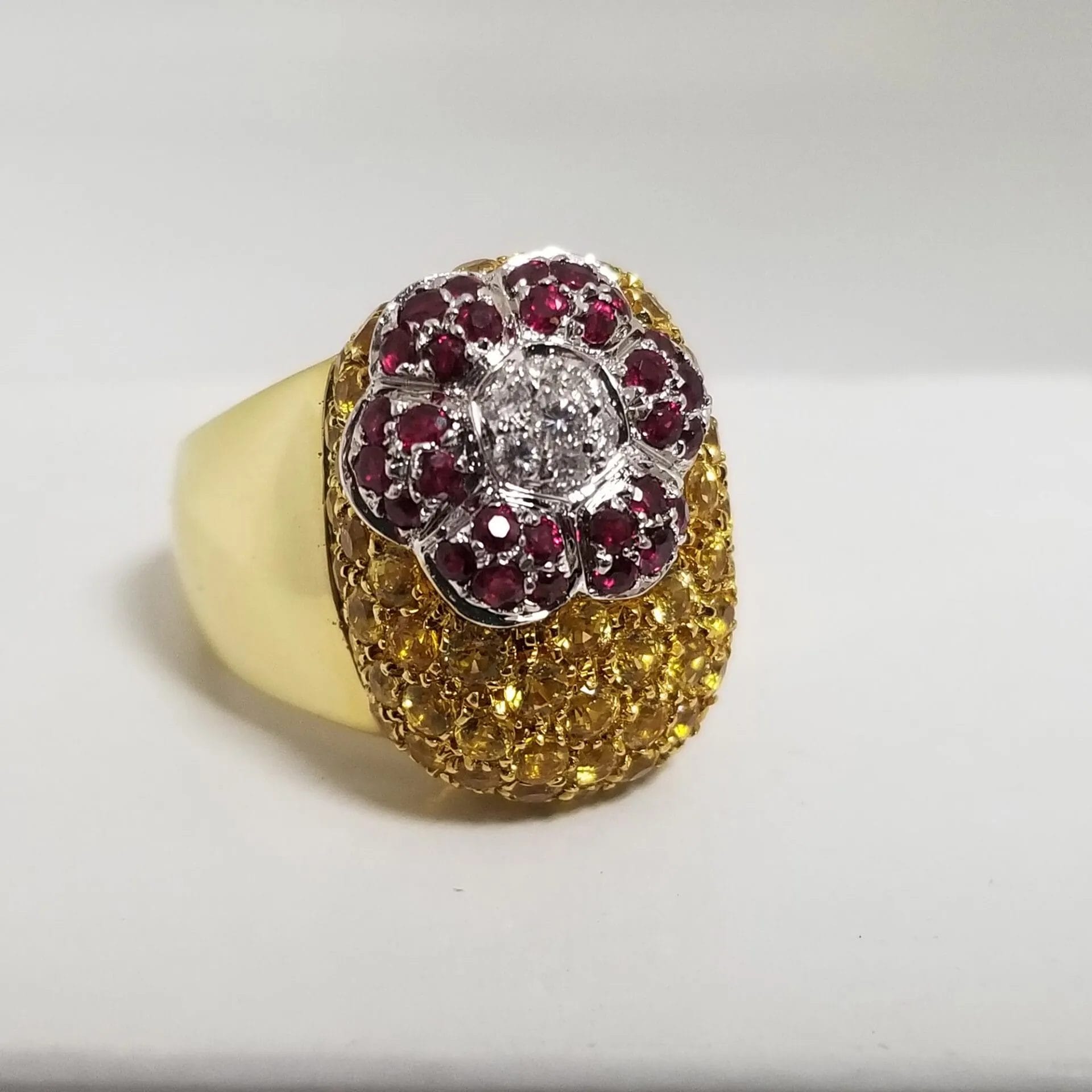 A yellow gold ring with red and yellow diamonds.