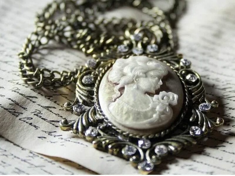 A cameo necklace is sitting on top of an old book.