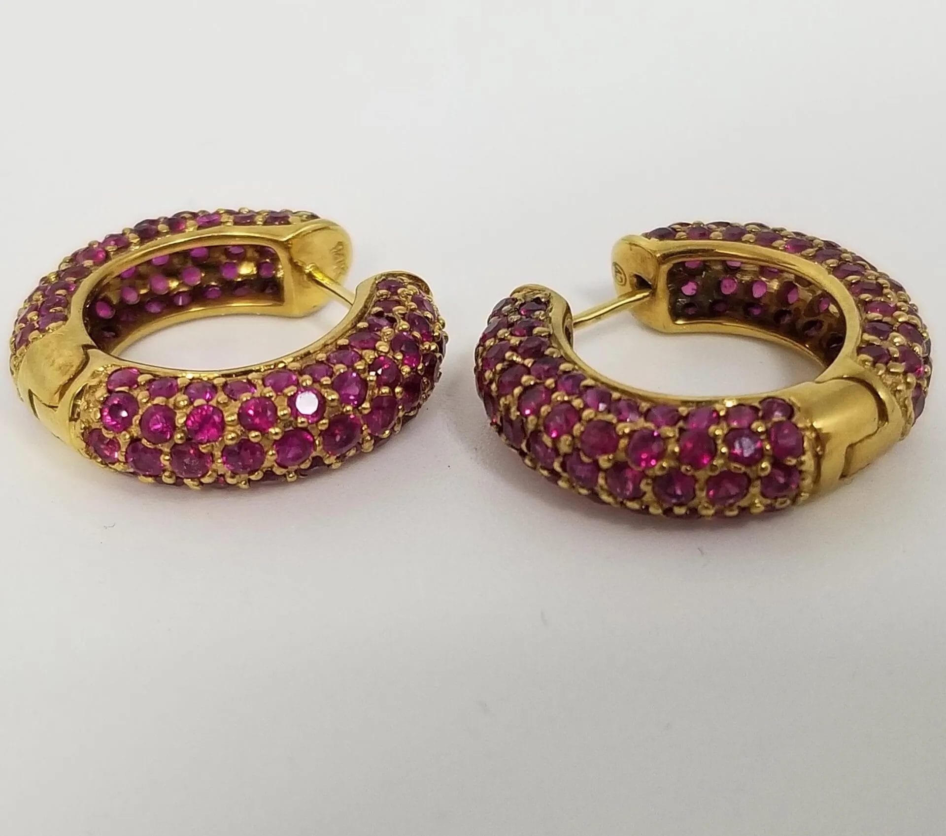 A pair of gold hoop earrings with pink stones.