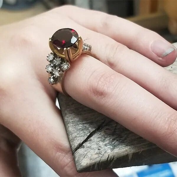 A woman wearing a ring with a garnet stone.