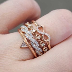 A woman's hand holding a stack of rings with diamonds.