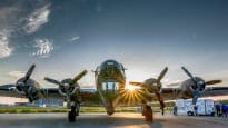 A propeller plane sits on the tarmac at sunset.