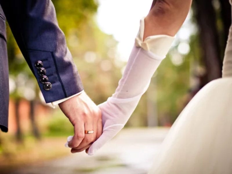 A bride and groom holding hands in a park.