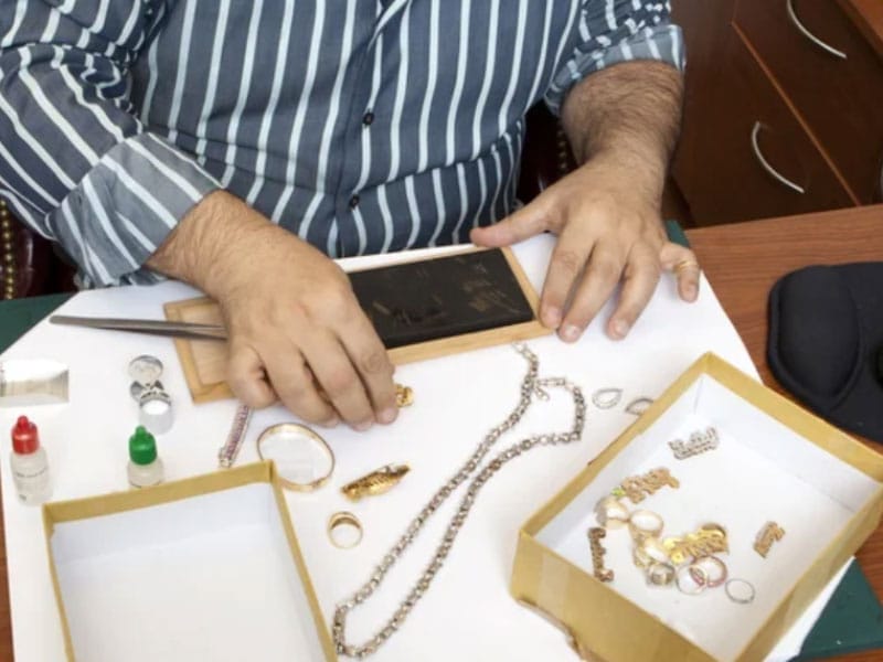 A man is working on an appraisal of some jewelry.