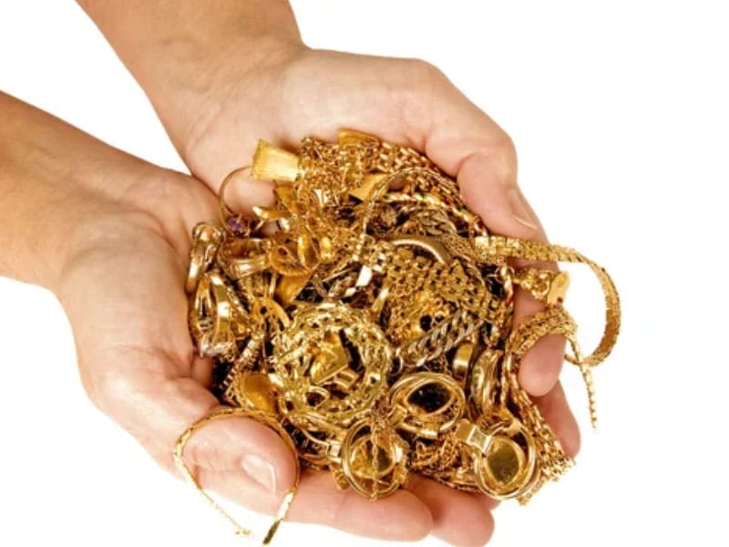 A woman's hands holding a pile of gold jewelry.
