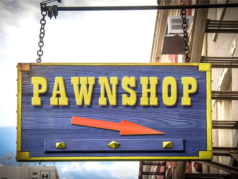 A sign that says pawnshop hanging from the side of a building.