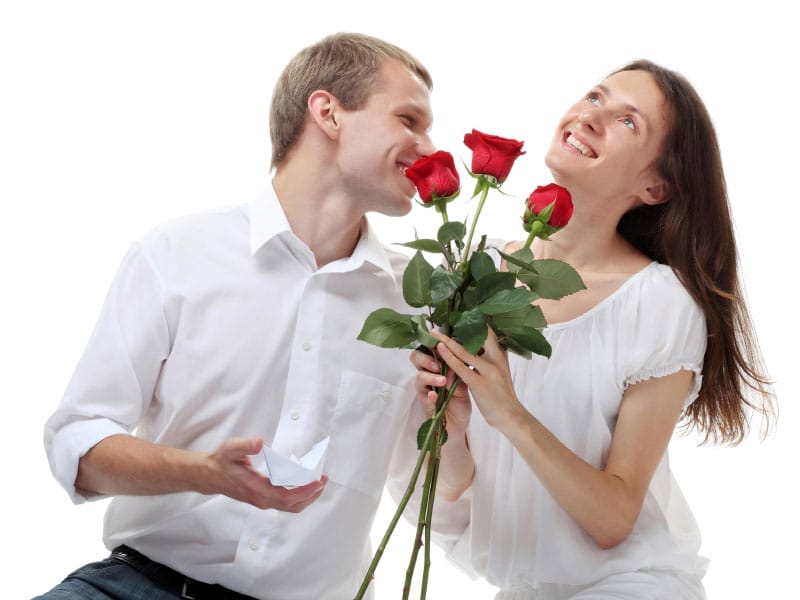 A man and woman holding a bouquet of roses before a marriage proposal.