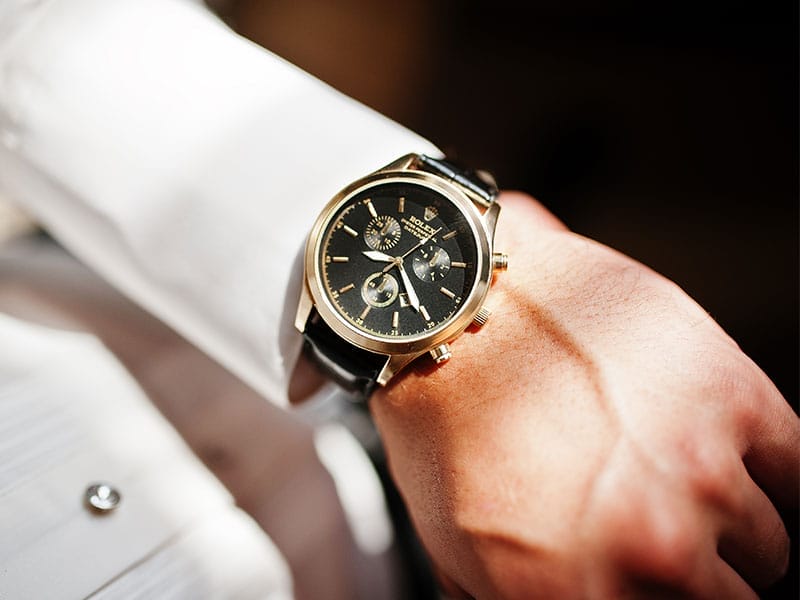 A man's wrist with a Rolex watch on it.