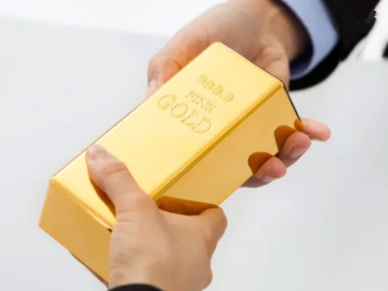 A person handing a gold bar to another person after a sale.