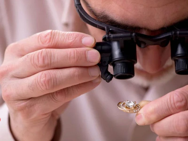 A man is looking at a gold ring doing an appraisal.