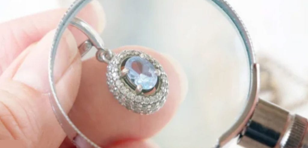 A person holding a magnifying glass over a diamond.