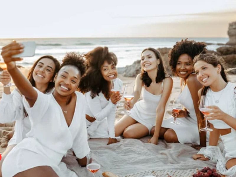 A group of women taking a selfie on the beach during a Bachelorette Party.