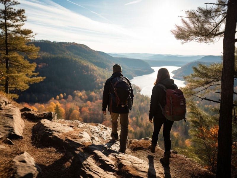 Two people hiking on a rocky cliff overlooking a lake & transitioning into married life.