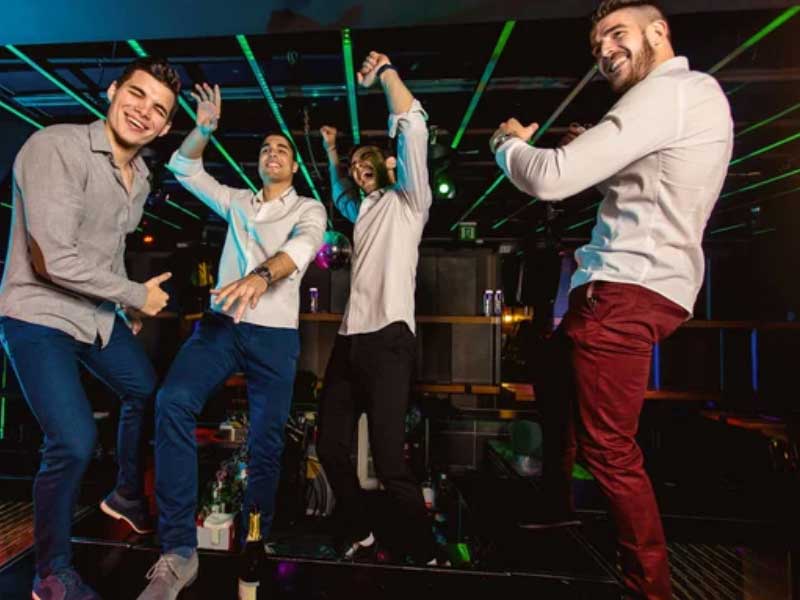 A group of men dancing in a nightclub during a Bachelor Party.