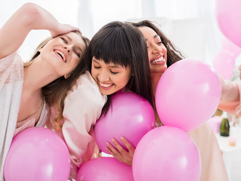 A group of women holding pink balloons at a Bachelorette Party.