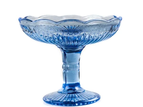 A blue glass pedestal bowl with a scalloped edge and ornate detailing.