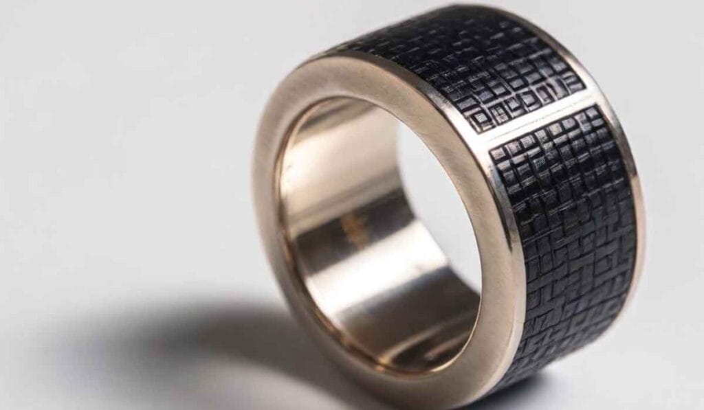 Close-up of a wide ring with a black textured pattern on the outer surface and a smooth inner band.